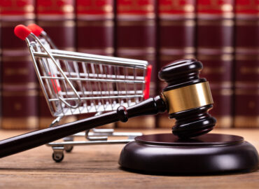 Close-up Of Brown Gavel And Shopping Cart In Front Of Law Books